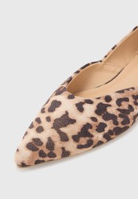 Spetsiga flats med ett leopardsmönster, tillverkade av mjukt material med en beige bas och mörkbruna detaljer. Slät textur.