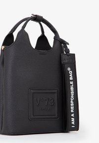 Borsa a tracolla in pelle nera texture con manici curvi, un'etichetta in rilievo "V°73 Venezia" e una tracolla nera con la scritta "I AM A RESPONSIBLE BAG".