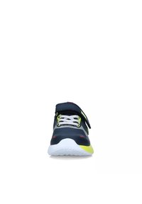 Scarpa sportiva con una tomaia sintetica blu scuro, dettagli gialli, suola in gomma bianca, cinturino in velcro nero e lacci grigi. Vista frontale.