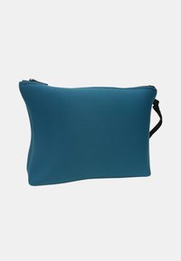 Borsa rettangolare blu con zip, leggermente gonfia, texture liscia e una tracolla nera su uno sfondo semplice.