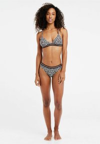 Crni bikini set s cvjetnim uzorkom i bijelim akcentima. Gornji dio ima trokutasti oblik s tankim trakama; donji dio je niskog struka.