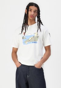 T-shirt de algodão branca com um graphic colorido de peixes e um farol, com mangas curtas e um corte descontraído.