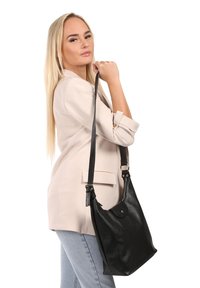 Zwarte leren handtas met een slungelige vormgeving, verstelbare schouderband en een ronde silhouette. Gladde textuur met subtiele hardwaredetails.