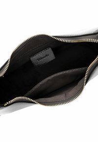 Zwarte leren tas met gouden ritssluiting. De binnenkant is gevoerd met zwarte stof en heeft een klein ritsvakje en een merklabel.