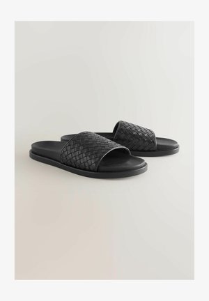 Czarne klapki na płaskiej podeszwie z plecionym paskiem i gładką fakturą. Wierzch wykonany z materiału syntetycznego.