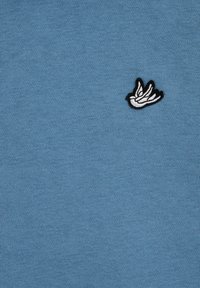 Țesătură de bumbac albastru cu o textură netedă, având un design brodat cu un păun alb, conturat în negru.