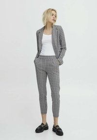 Completo a quadri in bianco e nero con giacca aderente e pantaloni tapered. Abbinato a mocassini neri con un accento dorato.