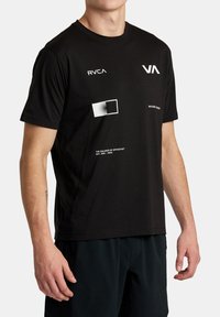 Čierne bavlnené tričko s grafickými potlačami v bielej farbe, vrátane štvorcov a textu. Okrúhly výstrih a krátke rukávy. Moderný, ležérny strih.