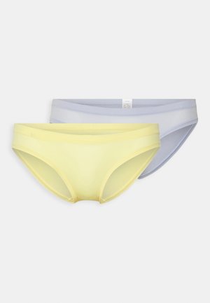 Zwei Paare Damenunterwäsche: eine hellgelbe und eine sanft lilafarbene, beide aus einem glatten, dehnbaren Material und mit minimalistischem Design.