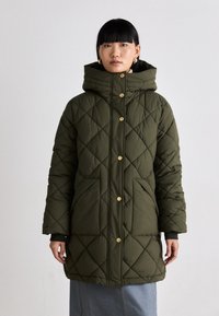 Gequilted pufferjack in donkergroen met een capuchon, voorzien van een knoopsluiting, diagonale stiksels en een lichte glans.