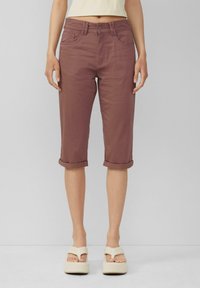 Bordowe spodnie cropped z podwiniętymi mankietami, wykonane z gładkiego materiału, z przednimi kieszeniami i zapięciem na guzik. Połączone z sandałami na platformie.