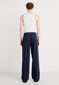 Pantalon à jambes larges bleu marine en tissu doux, avec une taille haute, des passants pour ceinture et deux poches arrière avec fermeture à boutons.