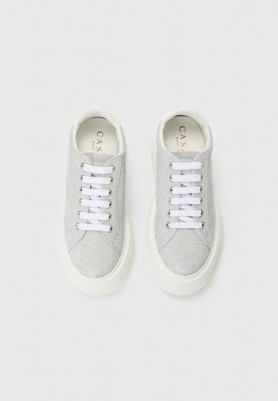 Silver sneakers with a textured finish, white laces, and a light-colored rubber sole. Logos visible on the insole.