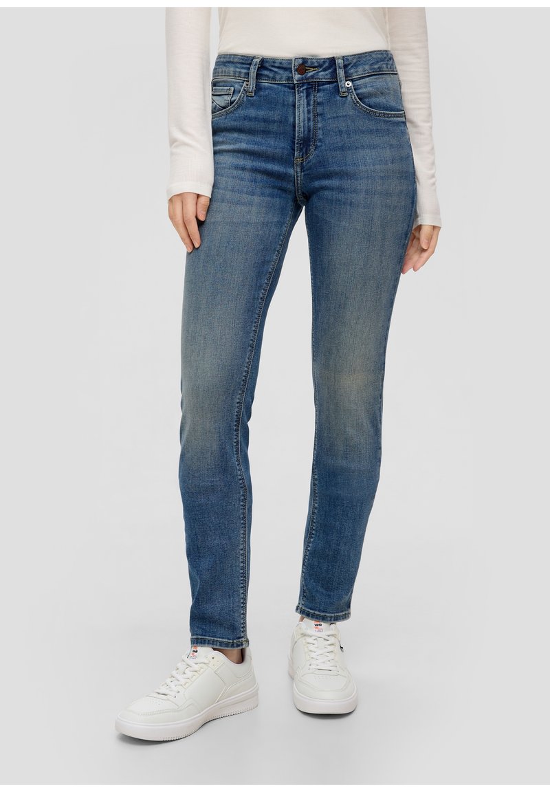 Blue denim jeans with a straight leg fit, five-pocket design, and subtle fading; paired with white sneakers and a long-sleeve top.