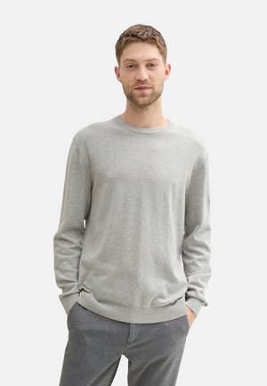 Suéter de cuello redondo en gris claro, hecho de un suave tejido de punto, con mangas largas y puños acanalados, combinado con pantalones grises.