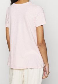 Light pink cotton t-shirt with short sleeves, round neckline, and a relaxed fit. Smooth texture, minimal design without visible branding.