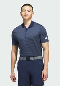 Navy polo shirt with a geometric pattern, short sleeves, and a collar. Paired with navy shorts and a textured gray belt featuring a clasp.