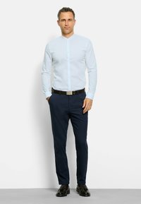 Lichtblauw overhemd met dubbele kraag, gecombineerd met marineblauwe broek en zwarte schoenen. Het overhemd heeft een gladde textuur en een slim fit.