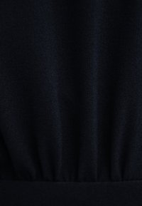 Ciemnoniebieska tkanina o gładkiej strukturze z marszczeniem w okolicy talii. Materiał wydaje się miękki i lekko błyszczący.