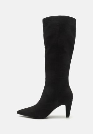 Botte noire en daim montant jusqu'au genou avec un bout pointu et un talon fin de hauteur moyenne, vue de côté sur fond blanc.