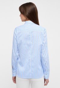 Camicia a maniche lunghe a righe azzurro chiaro e bianco con colletto a punta e polsini abbottonati, caratterizzata da una vestibilità rilassata e una texture del tessuto morbida.