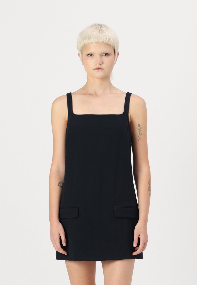 Robe sans manches noire avec un décolleté carré, dotée de deux poches avant. Fabriquée en tissu lisse, elle présente un design minimaliste et une coupe droite.