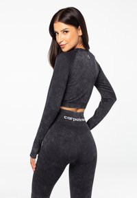 Sort, langærmet crop top med en blød tekstur, parret med højtaljede leggings med et "carpatree"-logo på taljen.