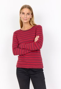 Red and dark red striped long-sleeve shirt with a round neckline, ribbed texture, paired with black jeans. Fitted design with a smooth finish.