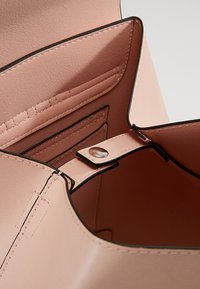 Poskipunanpunainen nahkainen käsilaukku, jossa on sileä pinta, kontrastiväriset mustat reunukset, sisäiset korttipaikat ja napsautettava suljin aukossa.