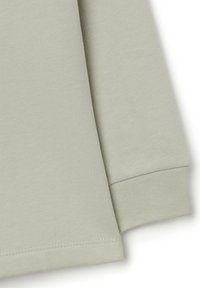 Light green sweatshirt fabric with a smooth texture, featuring a cuffed sleeve and flat stitching along the hem.