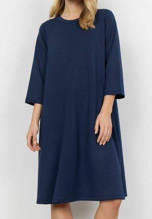 Robe t-shirt bleu marine, ample, avec manches trois-quarts, encolure ronde, et tissu doux et texturé. Longueur mi-mollet.