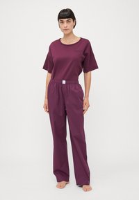T-shirt en coton violet à manches courtes et col rond, associé à un pantalon élastique assorti avec une coupe décontractée.