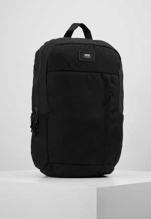 Sac à dos noir Vans avec une poignée supérieure, une poche avant zippée et un écusson avec le logo Vans sur une surface blanche unie.