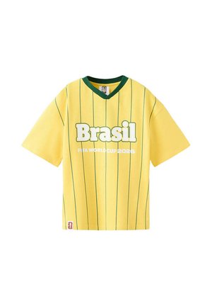 Maglia da calcio gialla a maniche corte con strisce verticali verdi, colletto verde, grande scritta "Brasil" e "FIFA World Cup 2026" sotto.