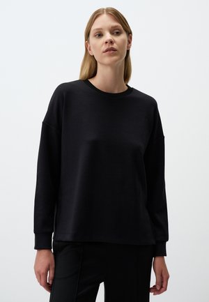 Felpa nera con maniche lunghe, scollatura a costine, vestibilità comoda, texture morbida e design minimalista. Indossata con pantaloni neri.