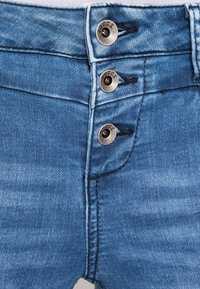 Pantalones cortos de mezclilla en azul medio con una cintura alta, que cuentan con tres botones metálicos y detalles cosidos a lo largo de los bolsillos.