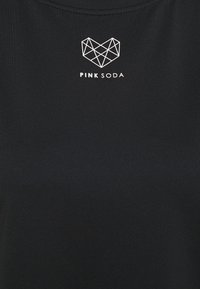 Černý textilní top s geometrickým logem srdce v bílé barvě a textem "PINK SODA" pod ním. Hladká textura a jednoduchý design.