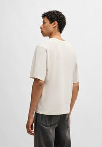Korte mouwen, crème katoenen t-shirt met een ronde hals, losse pasvorm en rechte zoom. Draag met donkergrijze denim broek.