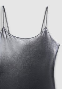 Top a spaghetto argento metallico con una texture liscia e lucida e una vestibilità morbida. Presenta un collo rotondo e spalline sottili regolabili.