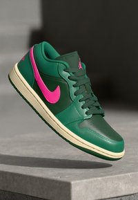 Ténis Nike Air Jordan com um cabedal em pele verde, pormenores em rosa, uma entressola creme e uma sola preta com detalhes perfurados.