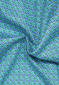 Textiel met een groen en blauw bladmotief op een lichtblauwe achtergrond, met een soepele textuur en een subtiele geweven structuur.