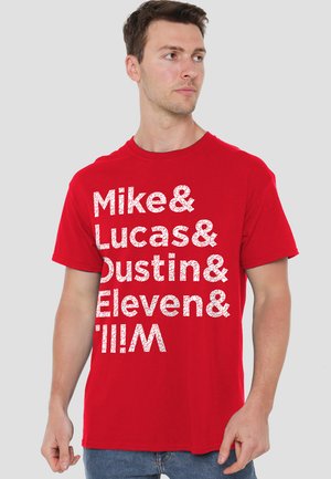 Red cotton t-shirt featuring bold white text with names arranged vertically. Crew neckline and short sleeves, casual fit.