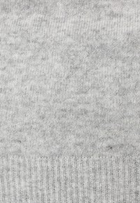 Tissu tricoté gris avec une texture douce, featuring une bordure côtelée en bas et un motif monochromatique légèrement varié.