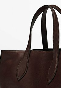 Bruine leren tote bag met twee lange handvatten, gladde textuur, strakke lijnen en contrasterende stiksels langs de randen en het handvat.