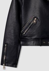 Giacca cropped in pelle nera con zip asimmetrica, dettagli con borchie e hardware argentato su tasche e cinturini.