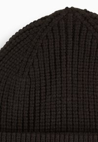 Mørkebrun strikket beanie med vertikal ribbet tekstur, som har en afrundet top og en folded cuff i bunden for ekstra varme.