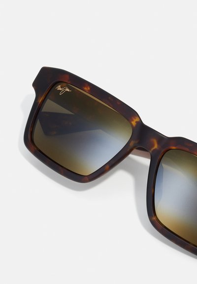 Tortoiseshell sunglasses with a chunky frame, dark gradient lenses, and gold logo detail. Textured finish with smooth edges.