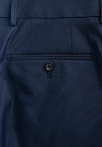 Navyblaue Stoffhosen mit einer glatten Textur, einer Gesäßtasche mit einem schwarzen Knopf und dezenten Nähten entlang des Randes der Tasche.