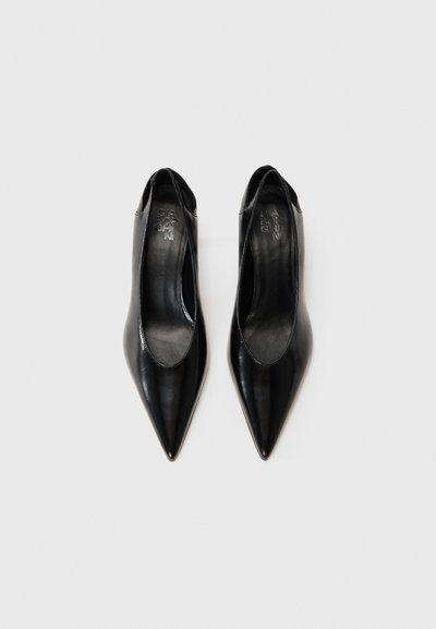 Svarta läderklackar med spetsig tå och slingback-design har en slät yta och öppna sidor, med präglad logotyp på innersulorna.