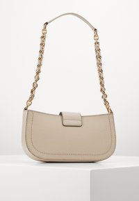 Sac à main beige avec une forme incurvée, texture lisse et une chaîne en or. Il possède un fermoir à rabat avec des détails de couture minimalistes.